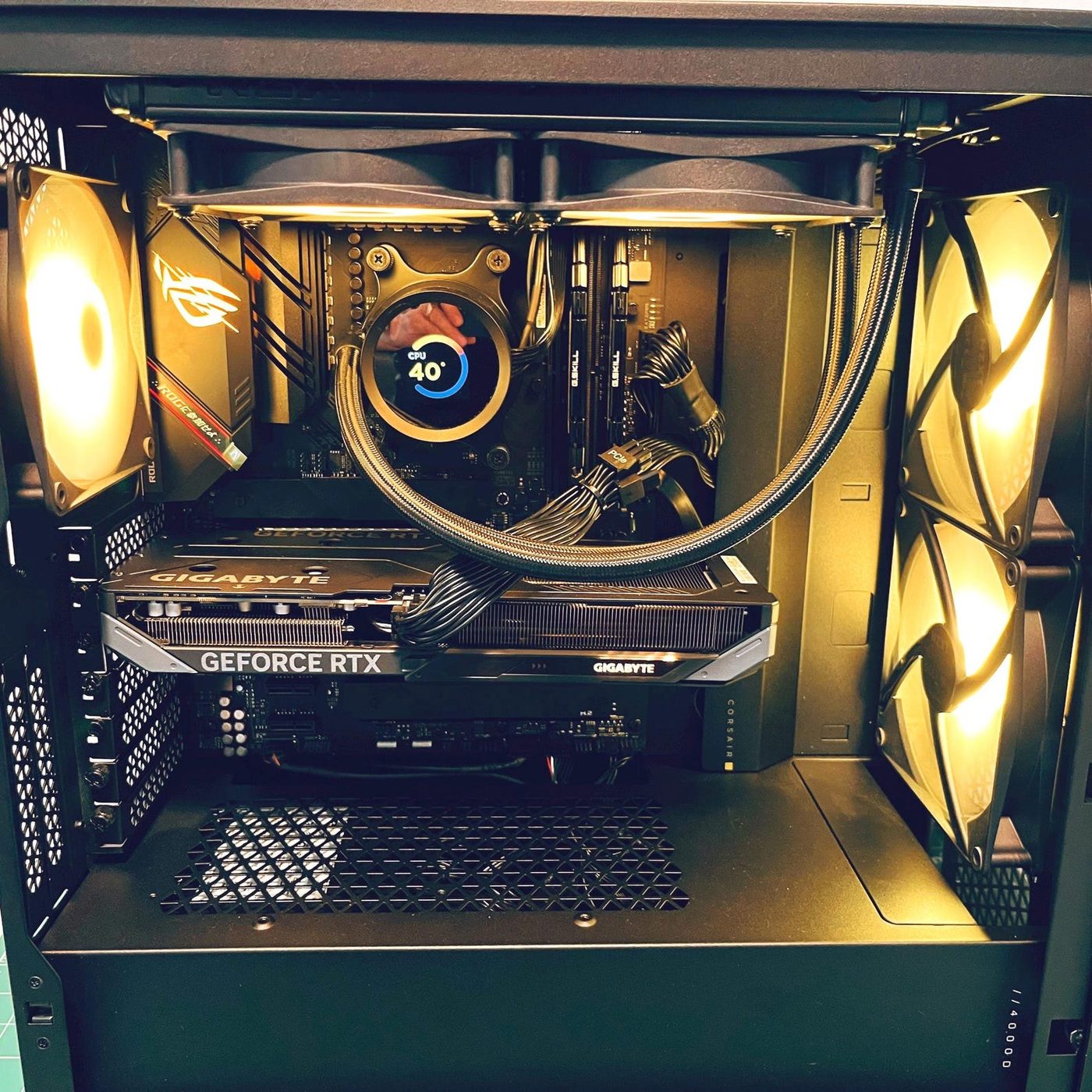 Black Corsair gaming PC with a Gigabyte GeForce RTX card and an ROG Strix board in warm lighting, built by NG+ GameBuilds