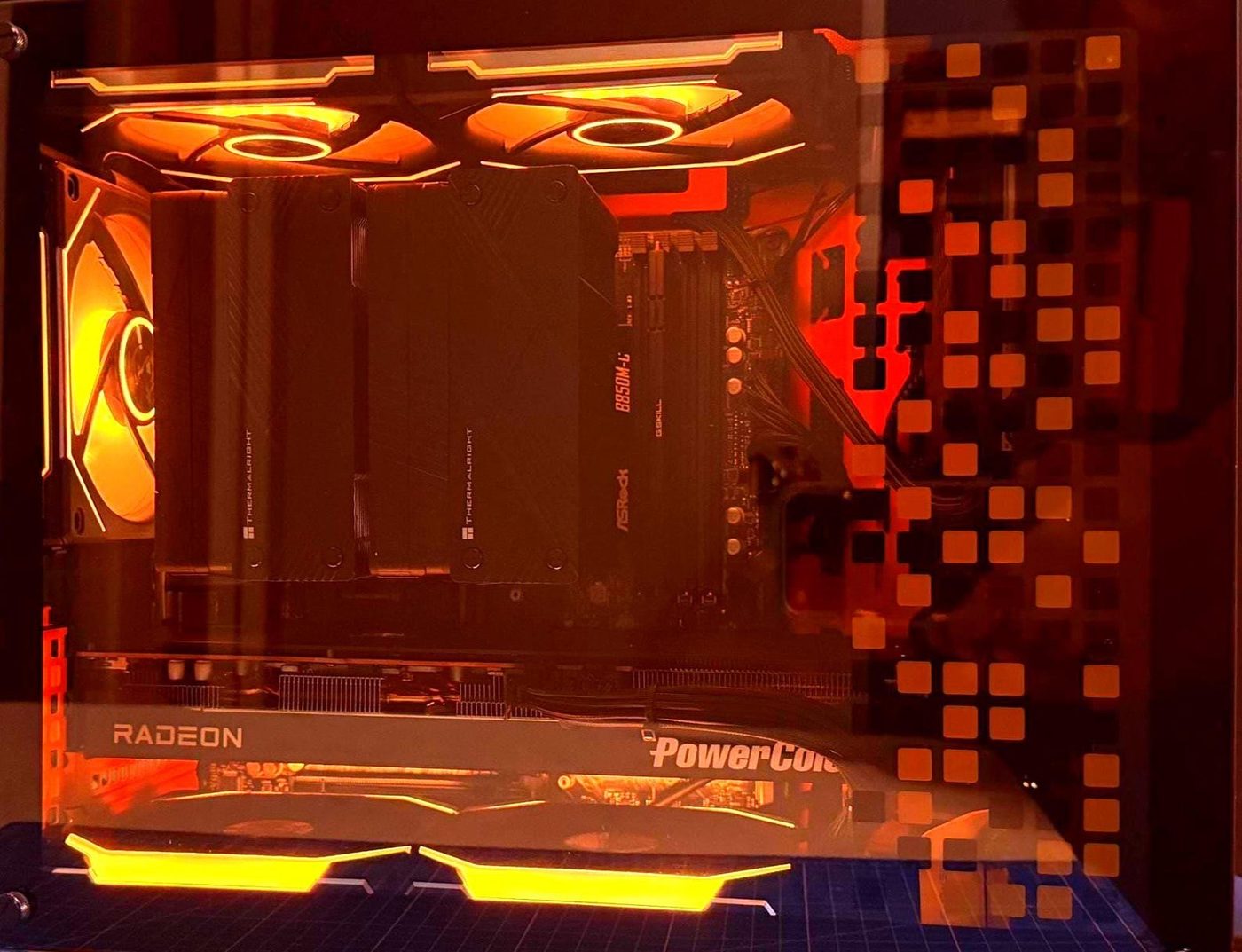 Gaming PC in amber lighting with a PowerColor Radeon card, Thermalright coolers and an ASRock B850M board, built by NG+ GameBuilds